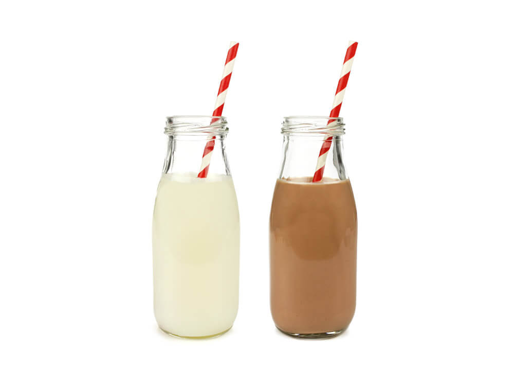 Glass bottles of milk with straws.