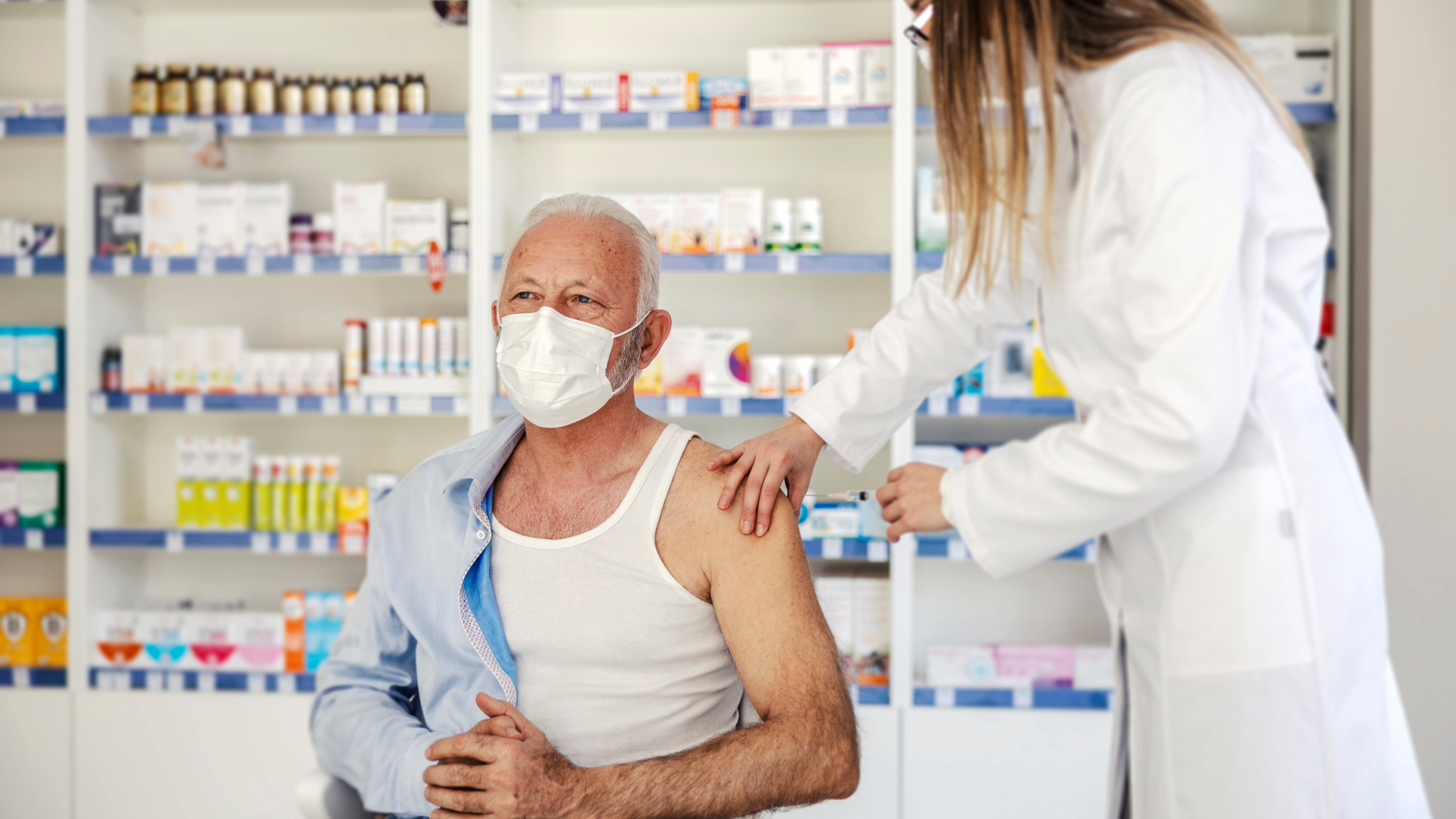 A pharmacist safely administers a vaccine to an older patient in a community pharmacy. 