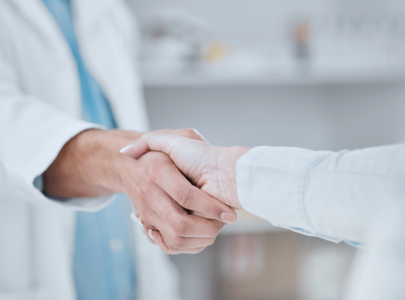 A pharmacist shakes hands with a stakeholder.