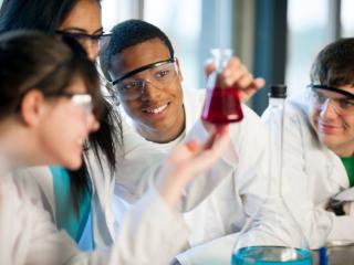 Whitecoat students studying beaker in the lab.