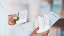 A pharmacist holds medication and paperwork.